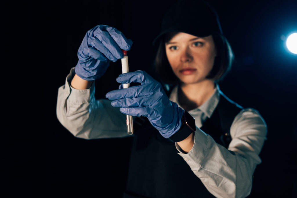 selective focus of investigator in rubber gloves holding swab and test tube at crime scene